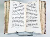 an open book with writing on it sitting on a metal stand