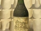 une bouteille de vin posée sur une table devant un mur de tasses