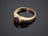 a gold ring with a purple stone on a black surface