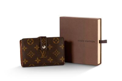 Le portefeuille Louis Vuitton se trouve à côté d'un livre