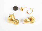 deux paires de boucles d'oreilles en or et une boucle d'oreille en or posées sur un fond blanc