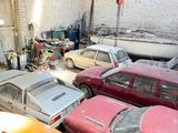 many old cars in a garage that is being worked on