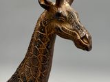 une statue de girafe qui se dresse dans l'herbe