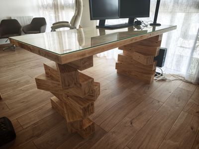 un bureau d'ordinateur avec un plateau en verre et un piètement en bois