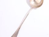 une cuillère en argent avec un manche de cuillère sur une surface blanche