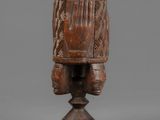 a wooden headdrek with a carved face on a pedestal