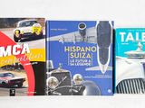 Plusieurs livres sont alignés sur une étagère posée sur une surface blanche