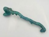 an image of a small green lizard on a stick on a white surface