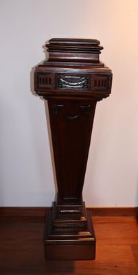 une horloge posée sur un socle dans un coin de la pièce