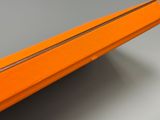 une valise orange munie d'une fermeture éclair sur le dessus, posée sur une table