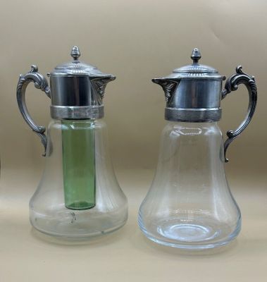 deux vases en verre munis de couvercles en argent et contenant un liquide vert