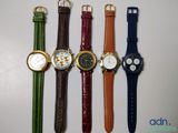 several different colored watches are lined up on a white surface