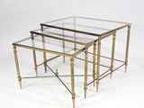 a pair of brass and glass nesting tables on a white background