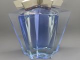 un flacon de parfum bleu avec un bouchon doré, posé sur une surface grise