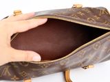 someone is holding a brown purse with a brown handle on a white surface