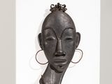un gros plan sur une sculpture représentant le visage d'une femme, posée sur une étagère