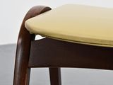 the back of a wooden chair with a yellow cushion on it
