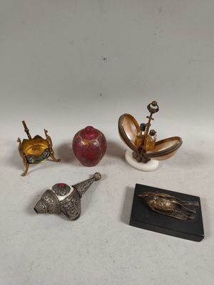 four silver and gold figurines of various shapes and sizes on a white surface