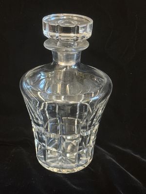 une bouteille en verre transparent munie d'un bouchon, sur fond noir