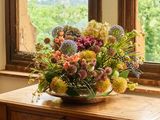 un vase de fleurs posé sur une table devant une fenêtre