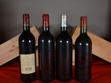 three bottles of red wine sit in front of a wooden crate