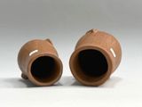 two brown vases sitting next to each other on a white surface