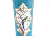un vase bleu orné d'un oiseau, posé sur une table