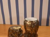two owl figurines sitting on a table next to a plate