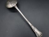 an antique silver spoon on a black surface with a black background