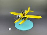 yellow model airplane with pilot sitting on top of it on a blue base