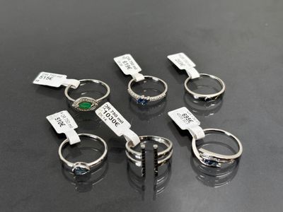 six bagues différentes, munies d'étiquettes, posées sur une table