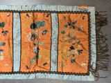 an orange and blue table runner with birds and flowers on it
