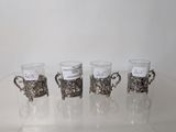 four cups with silver decorations are lined up on a clear table
