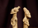 two figurines of two people on a table with a purple background
