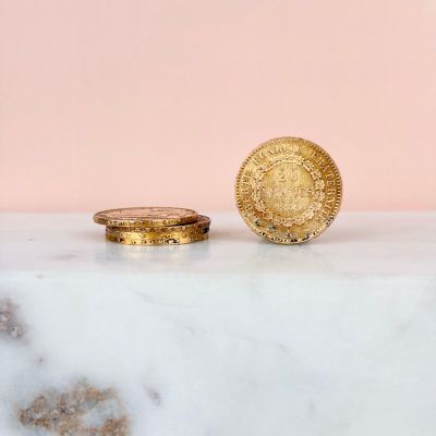 two gold coins sitting on top of a marble counter top