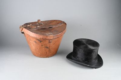 un chapeau noir et un seau marron posés sur une table blanche