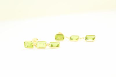 une paire de boucles d'oreilles en tourmaline verte posées sur un fond blanc