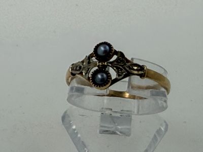 a gold ring with two black pearls on it