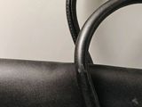 the handle of a black purse with a gold clasp on it