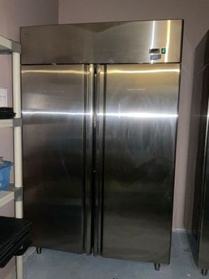 two stainless steel refrigerators in a kitchen next to a shelf