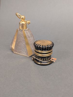 un objet doré et noir posé sur une table, à côté d'une bouteille en verre