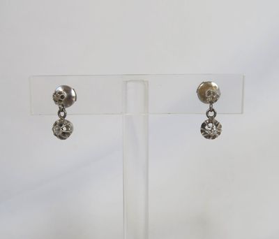 a pair of silver earrings on a clear display stand