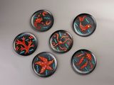 six glass magnets with red and blue designs on them on a white surface