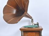 un vieux gramophone posé sur un support en bois, sur fond blanc