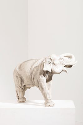 statue d'un éléphant debout sur un socle dans une pièce blanche