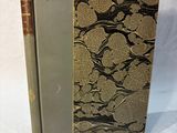 an old book sitting on top of a white cloth covered table