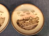 two plates with a picture of a city on them sitting on a table