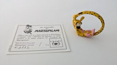 une bague jaune ornée d'une fleur rose, posée à côté d'une carte
