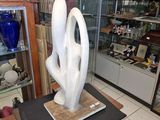 une sculpture blanche posée sur une petite table dans une pièce