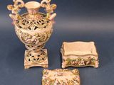three pieces of porcelain on display on a blue surface
